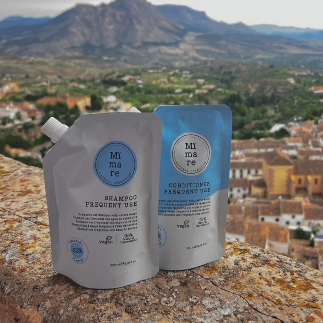 Mimare Frequent Use shampoo and conditioner pouches on stone wall with scenic mountain and village background - vegan natural hair care