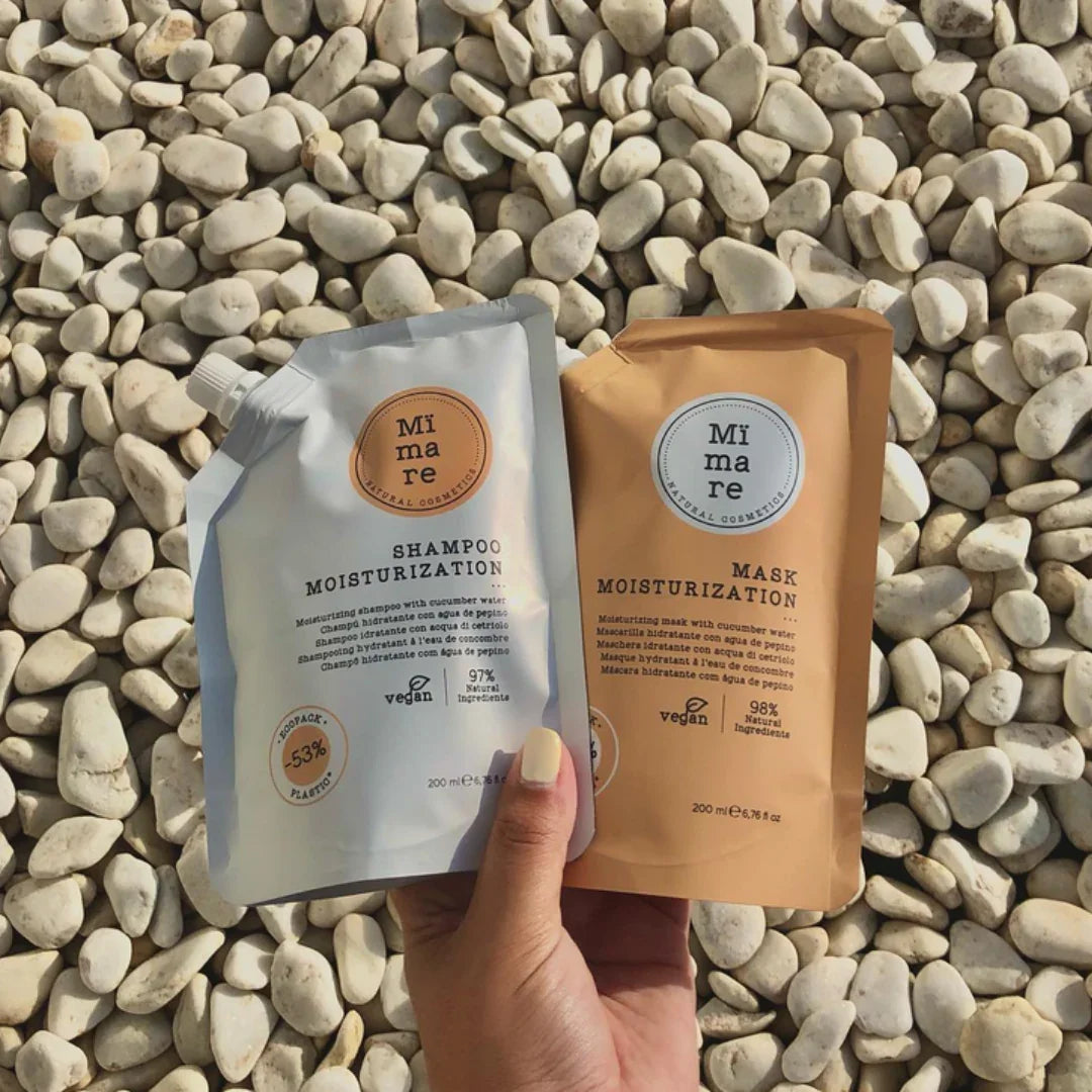 Hand holding Mimare Moisturization Shampoo and Mask pouches on white pebble background, vegan Korean hair care